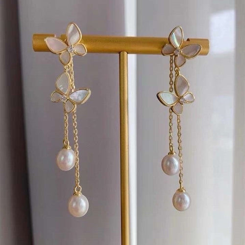 BoxUnboxed gold-plated brass butterfly tassel earrings with freshwater pearls and iridescent shell wings.
