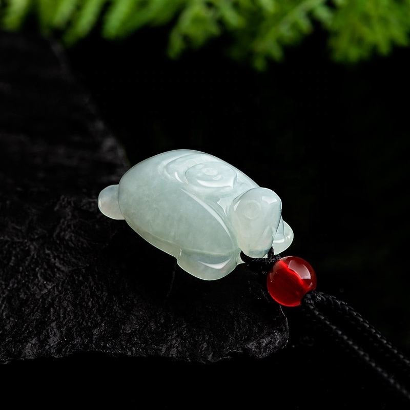 BoxUnboxed hand-carved natural Grade-A jadeite turtle pendant with a red bead on a black cord for protection.