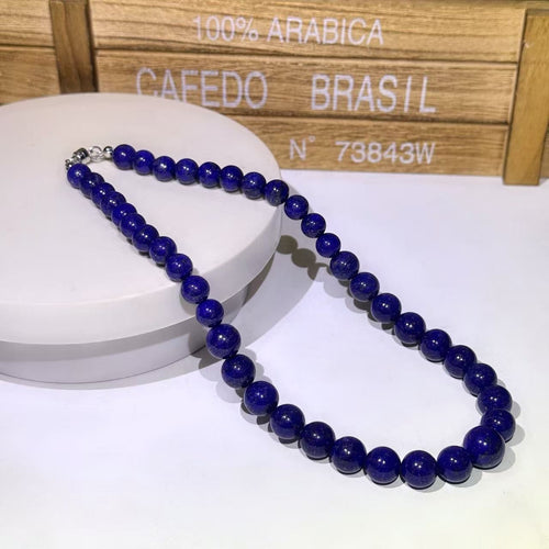 BoxUnboxed natural Afghan Lapis Lazuli beaded necklace with deep indigo stones and metallic clasp on a white display stand