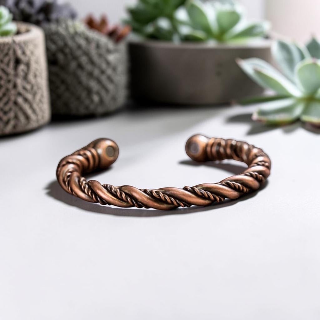 BoxUnboxed pure copper twisted wire cuff bracelet with magnetic end caps on a neutral surface with succulent plants.