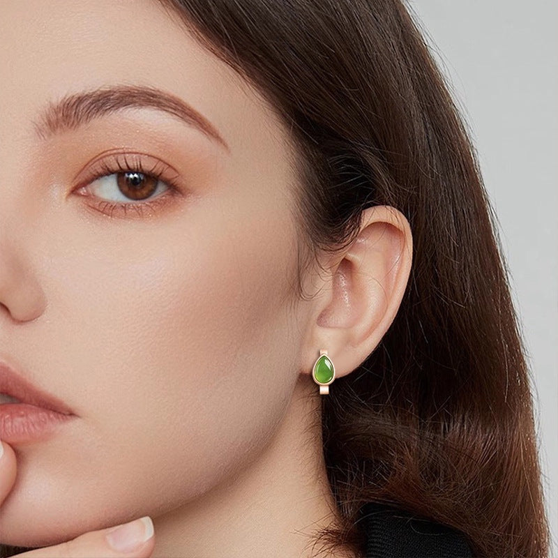 BoxUnboxed rose gold huggie earrings featuring a teardrop-shaped natural nephrite jade stone worn on a woman's ear.