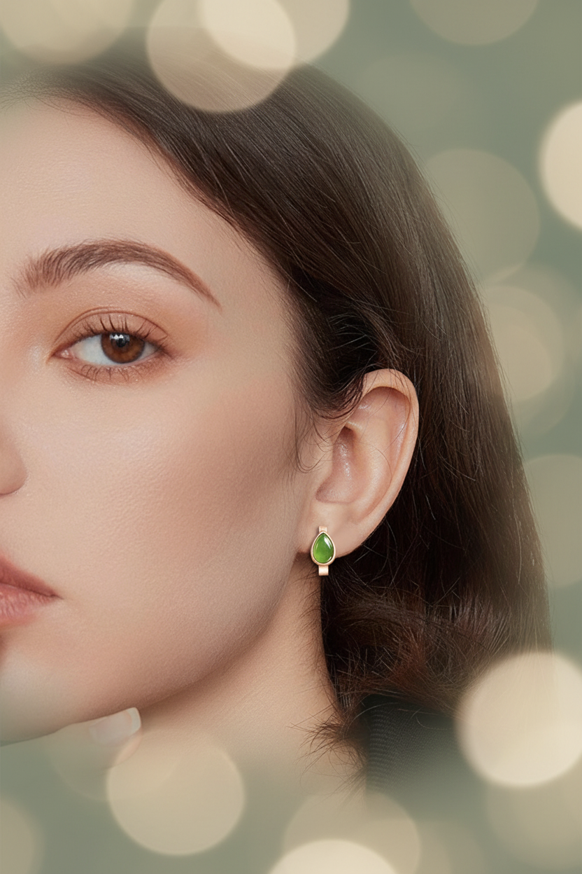 Editorial lifestyle shot of green jade huggie earrings on model, sage green bokeh background